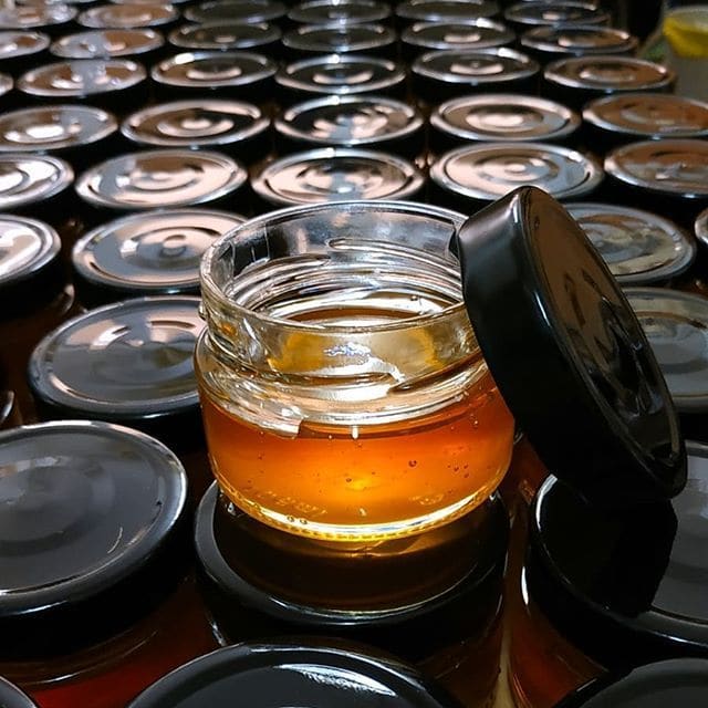 A golden jar of honey stands as a sweet treasure, its rich hue radiating warmth and the promise of natural goodness harvested from nature's bountiful embrace.